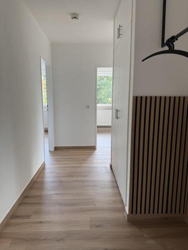 an empty hallway with white walls and wood floors at Neu renovierte Apartments mit 2 Schlafzimmern, Küche & Waschtrockner - 900 m Zentrum Borken in Borken