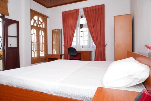 a bedroom with a bed and a desk and windows at The Mist Residence - Kandy in Kandy
