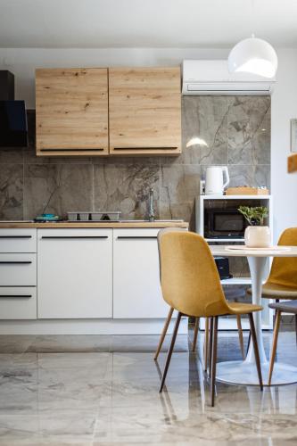 a kitchen with white cabinets and a table with chairs at Studio Apartman PlanB, self CHECK IN in Osijek