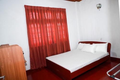 a bed in a room with a red curtain at The Mist Residence - Kandy in Kandy