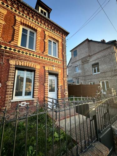 a brick house with a fence in front of it at Maison typique in Le Neubourg