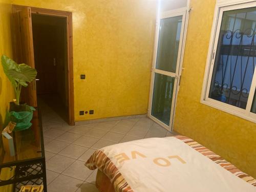 a bedroom with yellow walls and a bed and a window at Villa Chérine in Casablanca