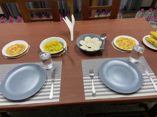 a table with plates of food and utensils on it at Berty's Cottage Home Stay in Jaffna