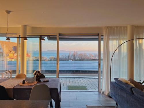 a living room with a table and a large window at Soleil House Saint Blaise in Saint-Blaise