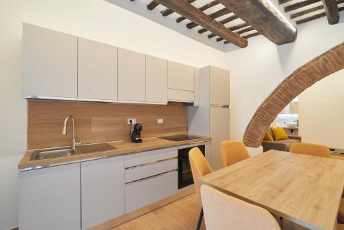 a kitchen with white cabinets and a wooden table at AM13 - Design retreat in Perugia