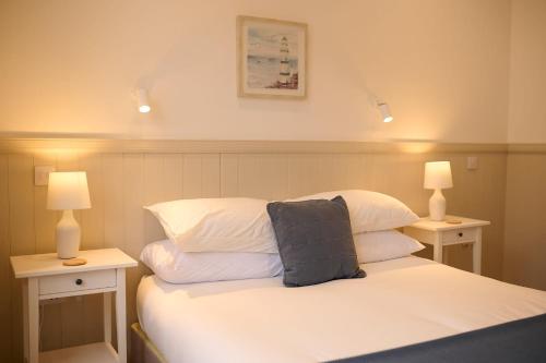a bedroom with a bed with white sheets and two lamps at Elegant 3BD Escape - Perfect Central Location in Oban