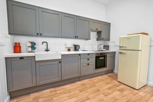 a kitchen with gray cabinets and a white refrigerator at Elegant 3BD Escape - Perfect Central Location in Oban