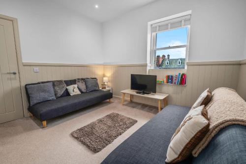 a living room with a couch and a television at Luxury 3BD Central Apt with Tower & Seaviews in Oban