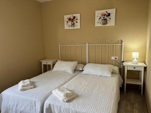 a bedroom with two beds with towels on them at Apartamento con huerta in San Mamede de Carnota