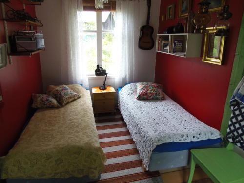 two beds in a room with red walls and a window at Gula Villan in Maxmo