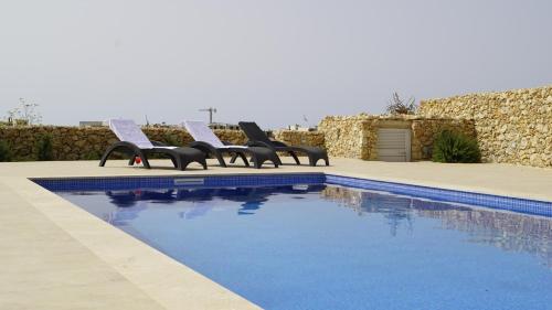 Un grupo de sillas junto a una piscina. en Pitt house, en Nadur