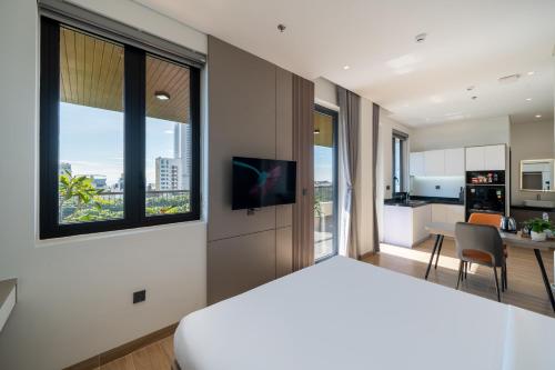a bedroom with a white bed and a kitchen at Sam Hotel & Apartment Da Nang in Da Nang