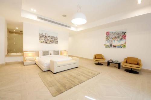 a bedroom with a white bed and two chairs at Royal Retreat Villa by Silk Valley at Nurai Island in Abu Dhabi