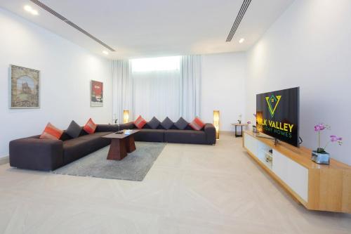 a living room with a couch and a tv at Royal Retreat Villa by Silk Valley at Nurai Island in Abu Dhabi