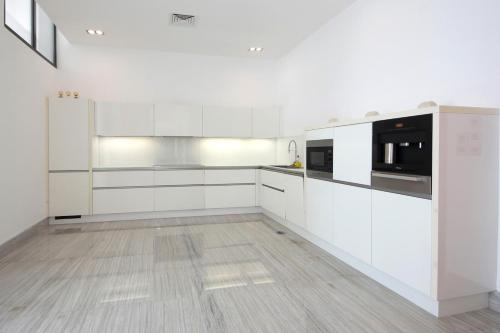 a white kitchen with white cabinets and a wooden floor at Royal Retreat Villa by Silk Valley at Nurai Island in Abu Dhabi