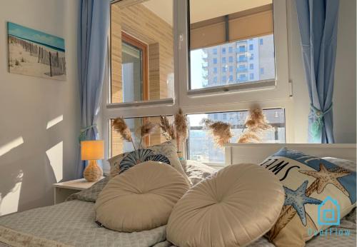 een slaapkamer met een bed met kussens en een raam bij Coast Apartment with Sauna & Gym, 5 Min to Baltic Sea & Polsat Plus Arena in Gdańsk