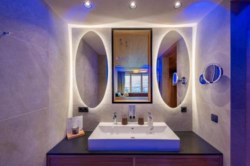a bathroom with a sink and two mirrors at Tratterhof Mountain Sky Hotel in Maranza