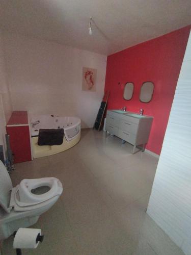 a bathroom with a toilet and a sink and red wall at Parfaite pour toutes direction in Fenain
