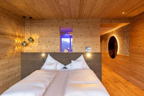 a bedroom with a large bed in a wooden wall at Tratterhof Mountain Sky Hotel in Maranza