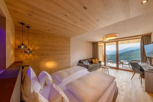 a bedroom with a large bed and a large window at Tratterhof Mountain Sky Hotel in Maranza