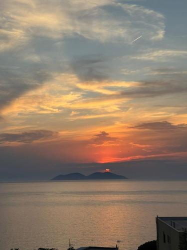 a sunset over the water with a mountain in the distance at Aloha Villa and Suites in Vlorë