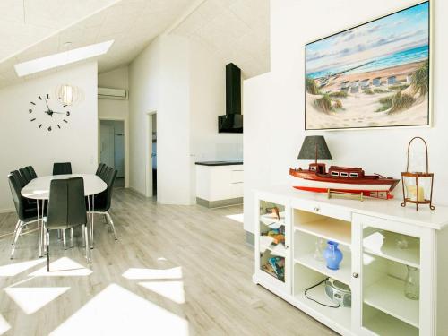 a white dining room with a table and a clock on the wall at Luxury Spa Retreat in Lokken - By Traum Ferienwohnungen in Løkken
