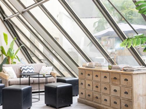 a room with a large window with a couch and stool at ibis Paris Alesia Montparnasse in Paris
