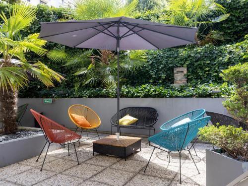 a group of chairs and an umbrella on a patio at ibis Paris Alesia Montparnasse in Paris