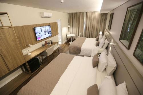 a hotel room with a large bed and a television at Hotel 4WOO in Telêmaco Borba