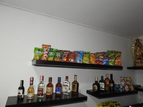 a wall with shelves with bottles of alcohol and snacks at Hotel Cielo de Tambores in Cali