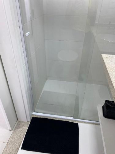 a shower with a glass door and a black rug at Apto moderno com ar-condicionado no Link Flats in Volta Redonda
