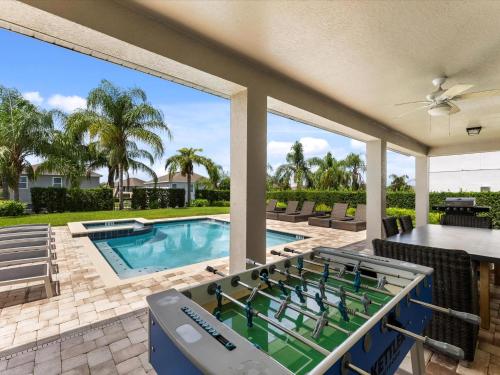 un patio con piscina, tavolo e sedie di Family Friendly Home With Private Pool, Game Room, Waterpark & Resort Access Near Disney At Encore Resort - 7638Wi a Kissimmee