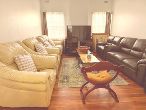 a living room with a couch and a chair and a table at Shipradi Homes - Prime location near shops & eatery in Sydney
