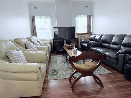 a living room with couches and a chair and a table at Shipradi Homes - Prime location near shops & eatery in Sydney