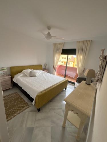 a bedroom with a bed and a table and a window at Las Colinas Beach in Manilva