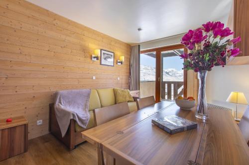 a living room with a couch and a table with flowers at Séjour à Val Thorens - Appartements au Pied des Pistes in Val Thorens