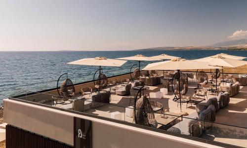 a restaurant with chairs and umbrellas on the water at Aminess Style Camping Avalona Resort - Pitches in Povljana