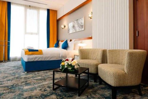 a hotel room with a bed and two chairs at Sunday Gateway Jeddah Formerly Beach Garden Hotel in Jeddah