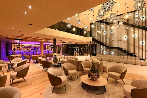 a lobby with chairs and tables and a staircase at Tratterhof Mountain Sky Hotel in Maranza