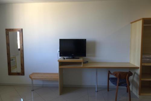 a room with a desk with a television and a chair at Itatiba Orion Hotel in Itatiba