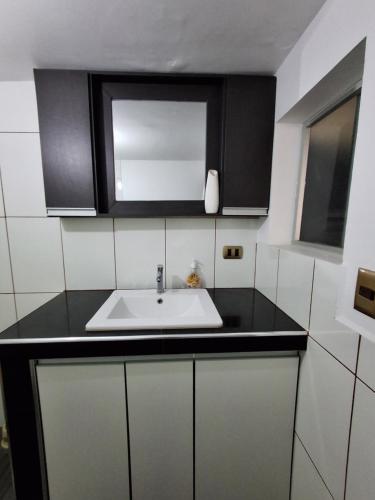 a kitchen with a white sink and black cabinets at Backpacker hostal oruro in Oruro