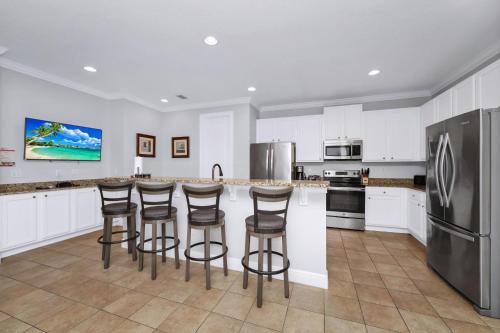 a kitchen with white cabinets and bar stools at Glorious Home Near Disney With Game Room, Themed Rooms, Waterpark & Resort Access At Encore Resorts Reunion - 7643Wi in Kissimmee
