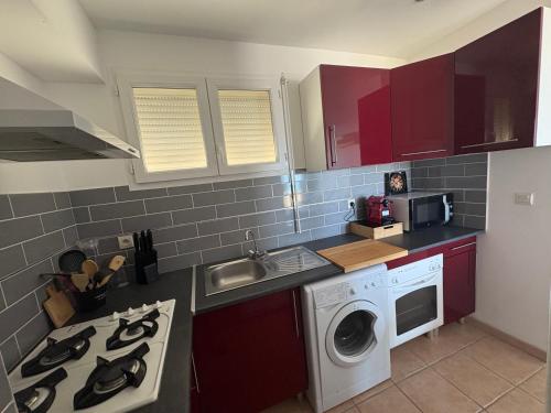 a kitchen with red cabinets and a washing machine at Apartment T2 with sea view in Saint Cyprien 50 m from the beach, parking in Saint Cyprien Plage