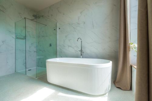 a white tub in a bathroom with a glass shower at Château de Looz in Borgloon