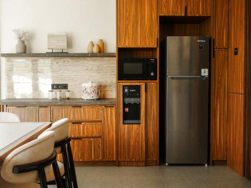 a kitchen with a stainless steel refrigerator and wooden cabinets at Theolive Arrea - Spacious Private Pool and Backyard in Warung Menteng