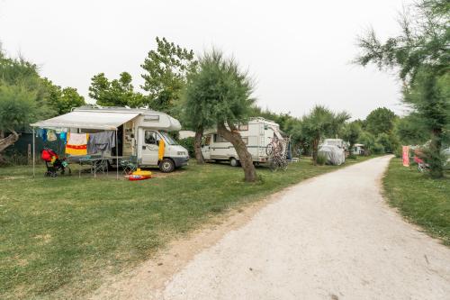 a group of vehicles parked in a field next to a dirt road at Club del Sole Vigna sul Mar Family Collection in Lido di Pomposa