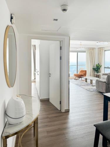 a living room with a table and a mirror at Relaxing 2-Bedroom Stay by the Sea Pacific Al Marjan in Ras al Khaimah