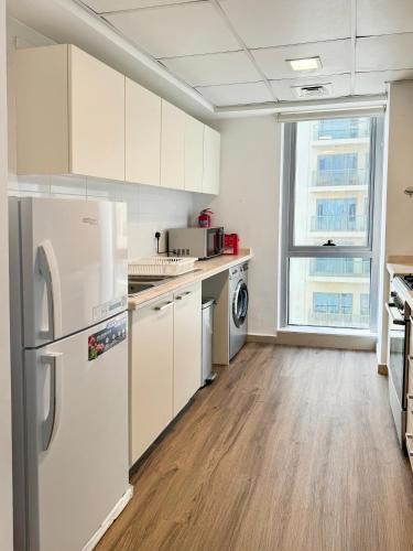 a kitchen with white cabinets and a refrigerator at Relaxing 2-Bedroom Stay by the Sea Pacific Al Marjan in Ras al Khaimah