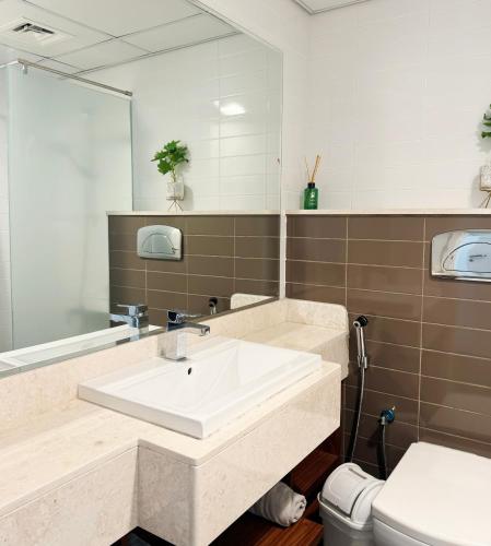 a bathroom with a sink and a mirror and a toilet at Relaxing 2-Bedroom Stay by the Sea Pacific Al Marjan in Ras al Khaimah