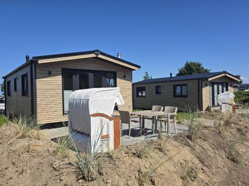 a house with a table and chairs in front of it at Ostseeferienpark Walkyrien - Lotse j in Kagelbusch